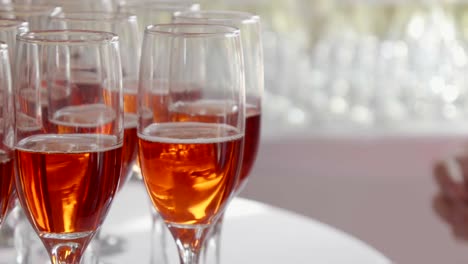 guests at a party taking glasses of red champagne from a tray