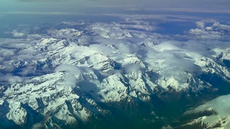 an elevated aerial view of the snowed swiss alps mountains taken from an airplane cockpit at spring.