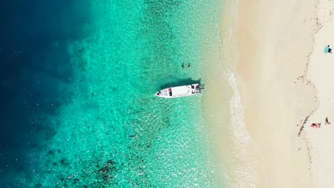 barco anclado en la orilla del mar de una isla tropical, turistas disfrutando de nadar en aguas tranquilas de color azul turquesa y tomando el sol en una playa blanca y exótica en república dominicana