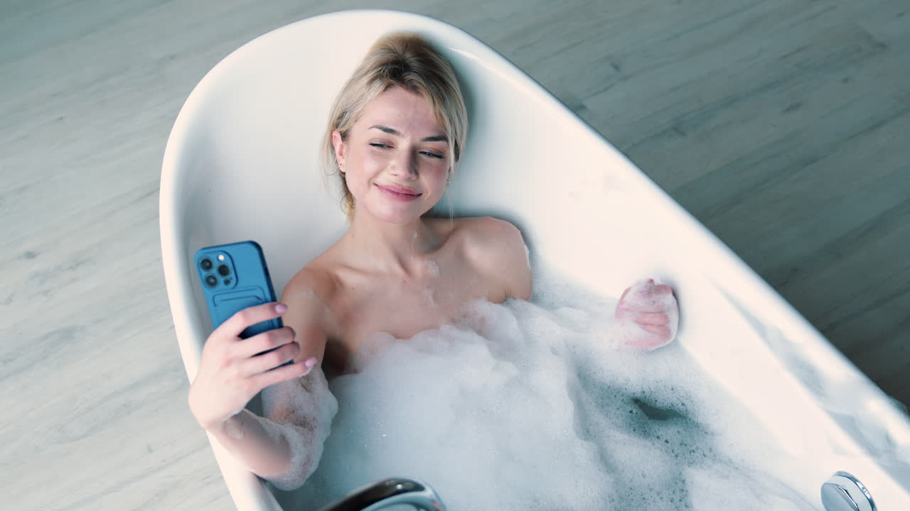 женщина отдыхает в пузырьковой ванне с телефоном