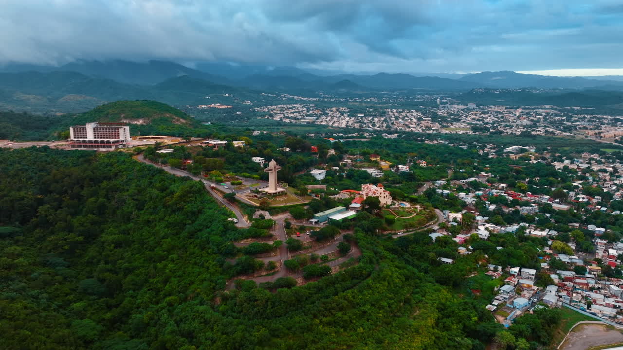 Avvicinandosi alla Croce del Guardiano situata sulla collina verde. Paesaggio di Ponce, Porto Rico circondato da montagne coperte da nuvole grigie.