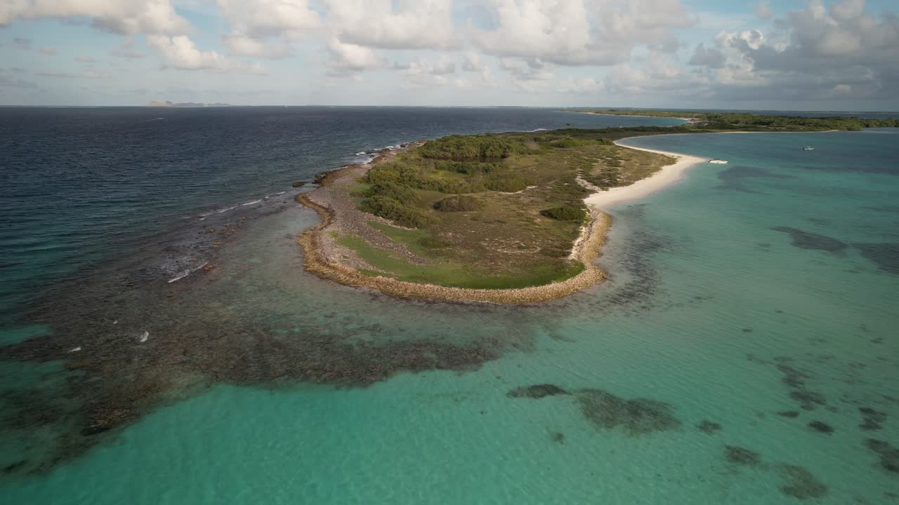 A scenic aerial view of a tropical island with lush greenery, turquoise waters, and sandy beach