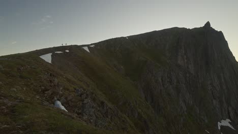 Hikers-reach-the-summit-of-Husfjellet-in-Norway's-Senja-at-sunset