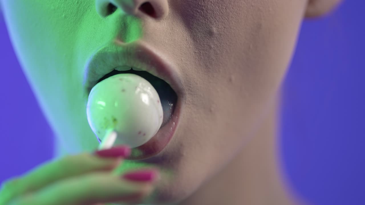 cerca de la boca de la mujer, chupando lame dulces de piruleta, colorido tiro de estudio