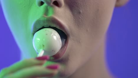 close up of woman's mouth, sucking licking lollipop candy, colorful studio shot