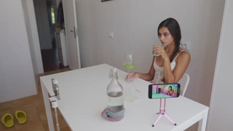 Woman at a table with a phone and a drink