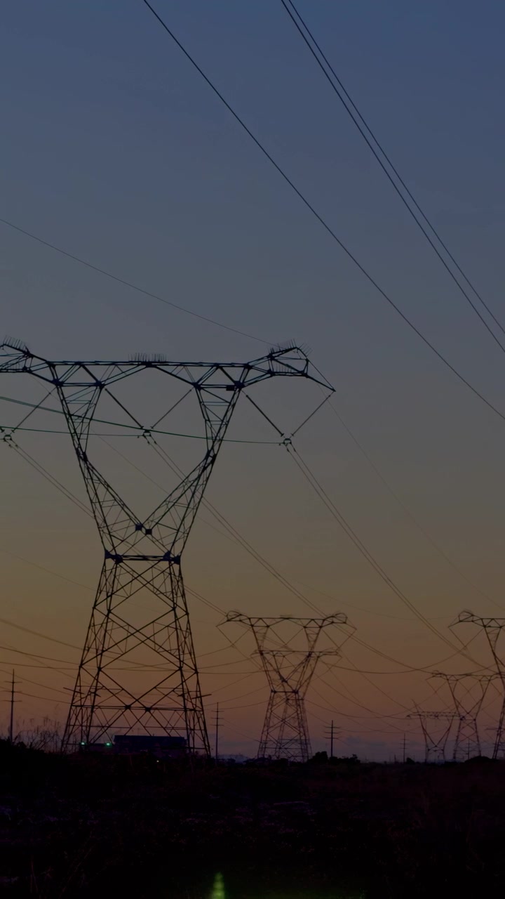 Vertical video: Lattice tower getting green arrows appearing, growing up showing power data at dusk