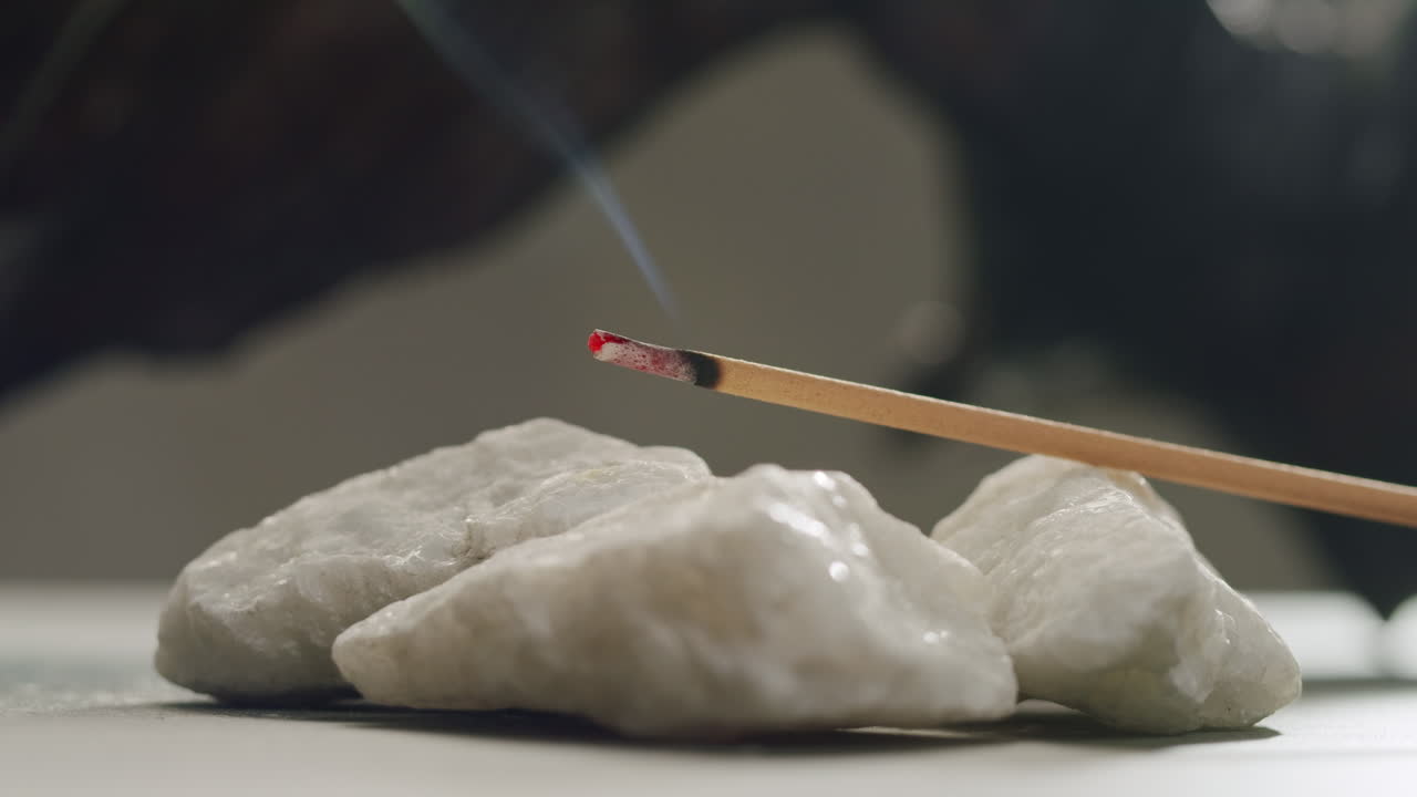 Person holding Palo Santo wood stick in hand, aromatic Palo Santo burning on black background, smoke spreading around, slow motion video clip, high quality 4k close up footage. High quality 4k footage