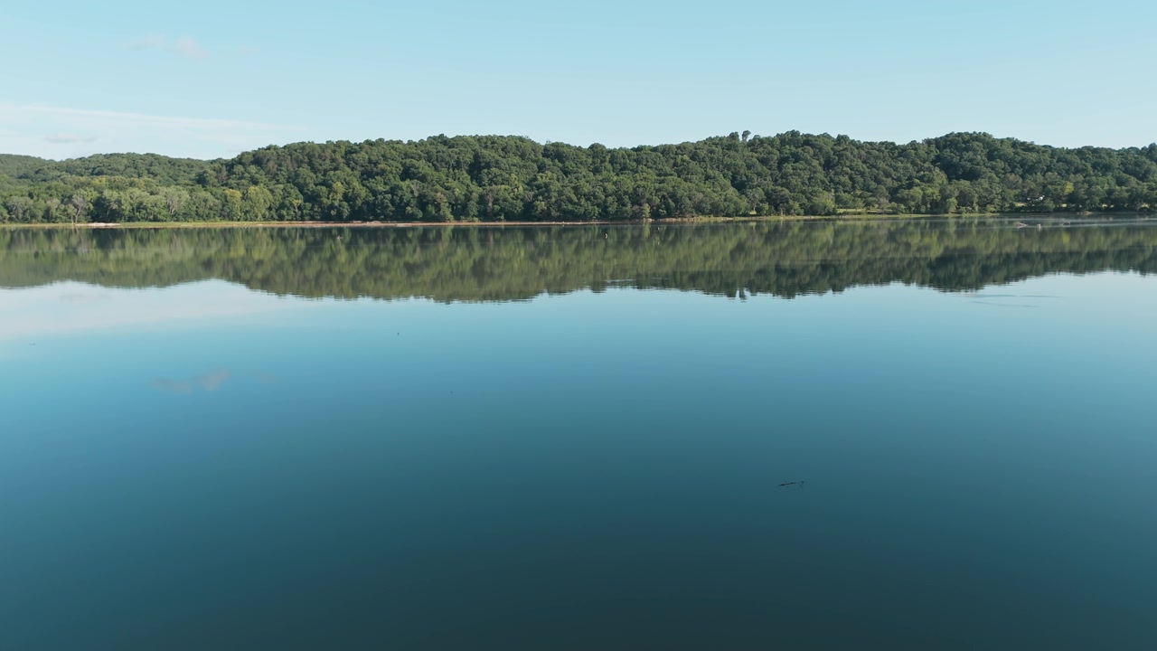 Vastes eaux calmes du lac Eucha reflétant le ciel bleu dans l'Oklahoma rural, plan aérien en recul.