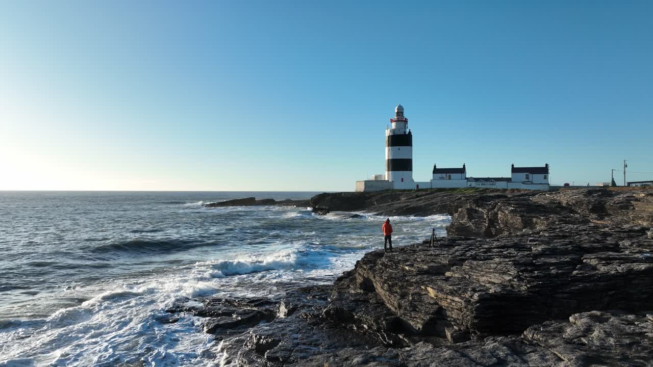 Paesaggi di fari irlandesi: il Faro di Hook Head con grandi onde che si infrangono sugli scogli in un giorno di primavera.