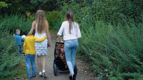 young mothers with children go into the distance on a forest