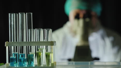 tubos de ensayo en el laboratorio mientras un hombre trabaja con un microscopio
