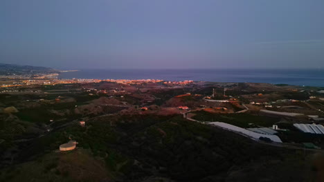 Vista-Aérea-De-Una-Puesta-De-Sol-Sobre-Málaga,-España,-Con-El-Mar-Y-Las-Montañas-Que-La-Rodean.