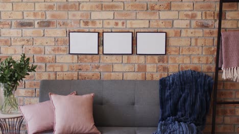 three wooden frames, plant and sofa with copy space on brick wall