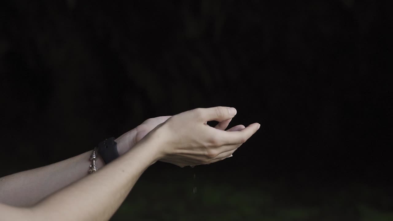 Young women's  exploring a cave and catching dripping water from its rocks