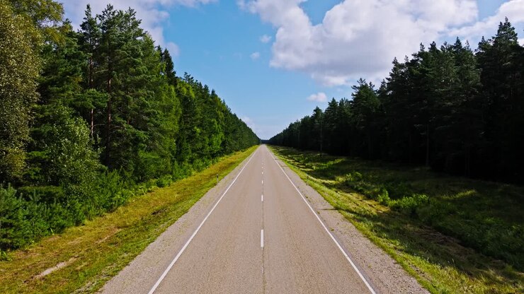 Drone che vola lentamente in avanti sopra un paesaggio boschivo autostradale deserto con clima ventoso