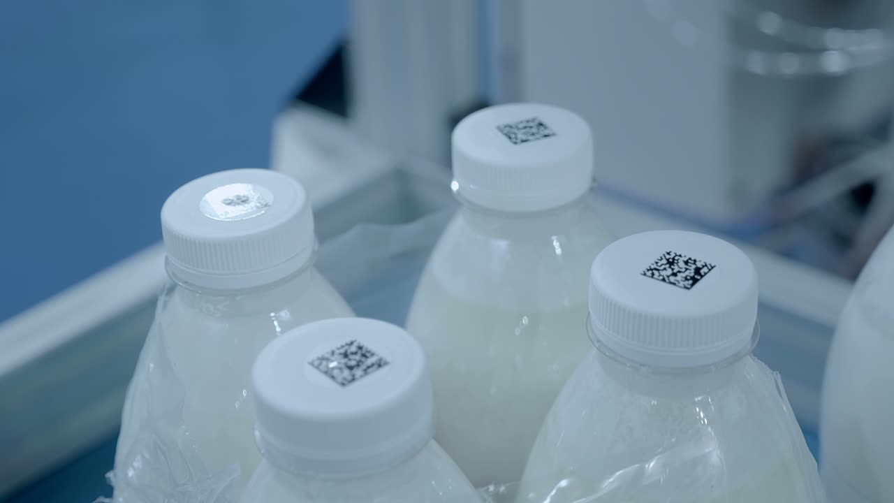 grupo de botellas de leche de plástico blanco con códigos qr pegados en sus tapas