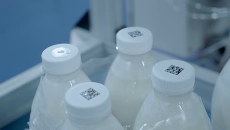 group of white plastic milk bottles with qr codes pasted on their caps