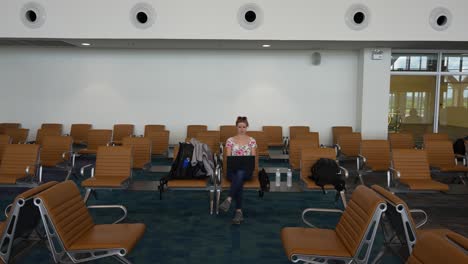 girl peacefully working on a computer in an airport empty room