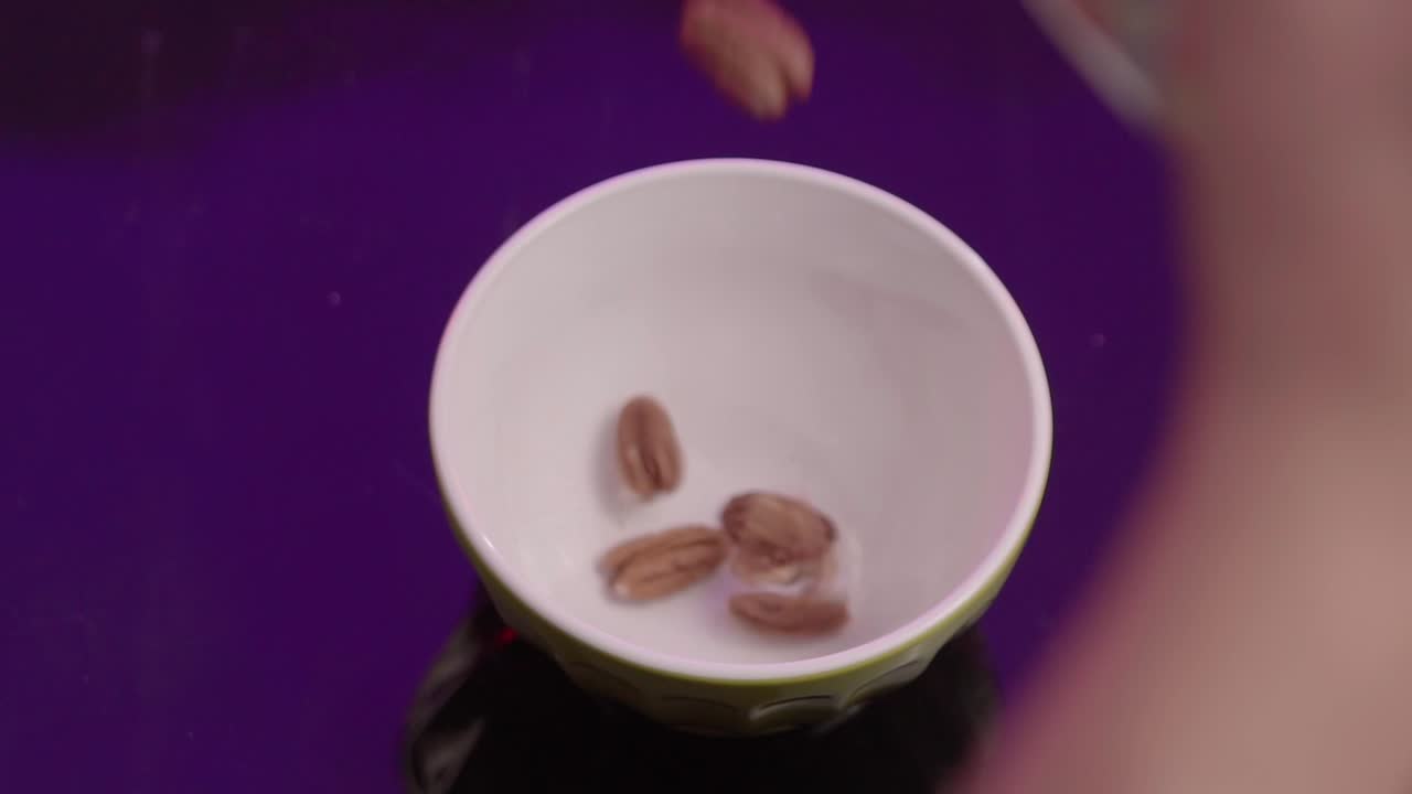Top down shot of walnut being poured into a bowl, interior, close up
