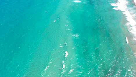 a cool drone shot of crystal clear waves rolling into a south florida beach