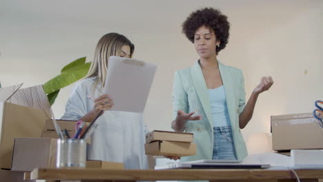 dos mujeres atractivas revisando paquetes para su envío