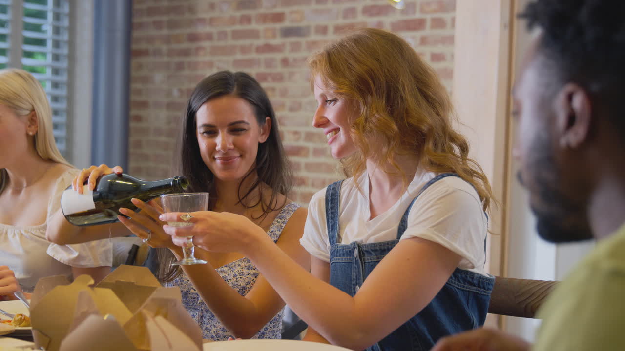 Multi-Cultural Group Of Friends Enjoying Drinks And Takeaway Food At Home Together