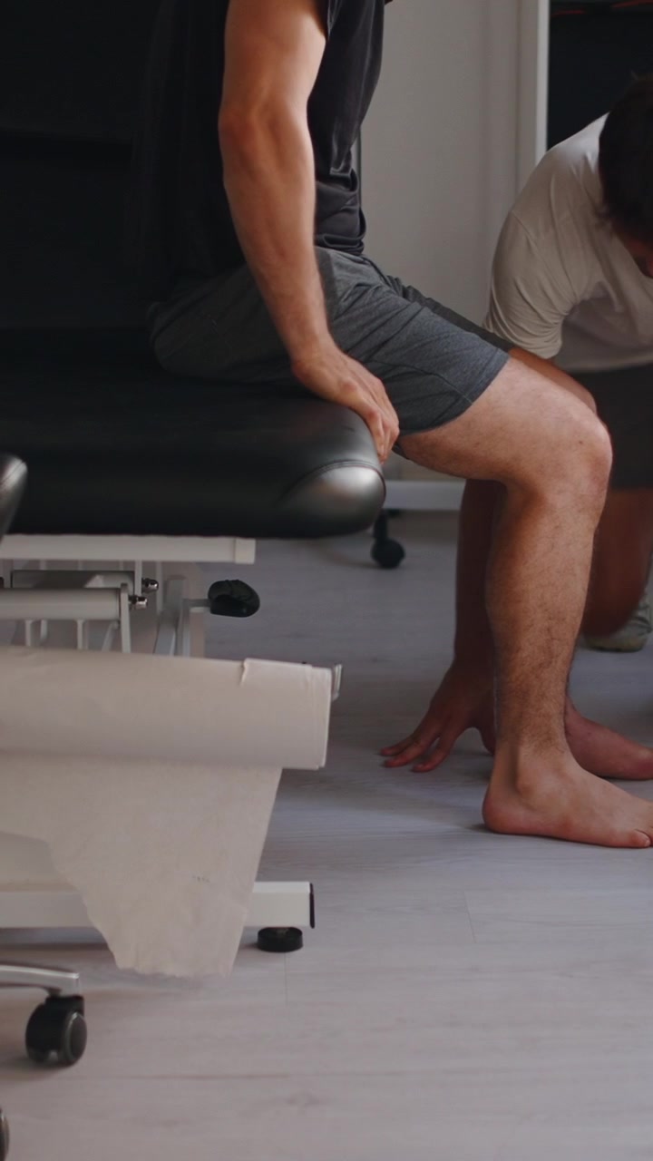 Physical Therapist Examining Patient's Injured Ankle in Clinic