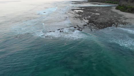 people enjoying on surf boards floating over the calm blue ocean with coral reef underwater in an island in costa rica - aerial shot
