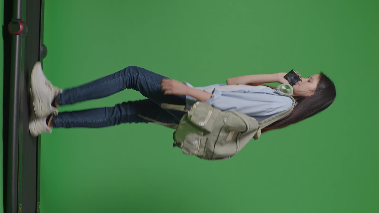 모습으로 가득 찬 몸의 아시아 십대 소녀 학생은 초록색 스크린 배경 스튜디오에서 트레드밀을 는 동안 스마트폰으로 이야기합니다.