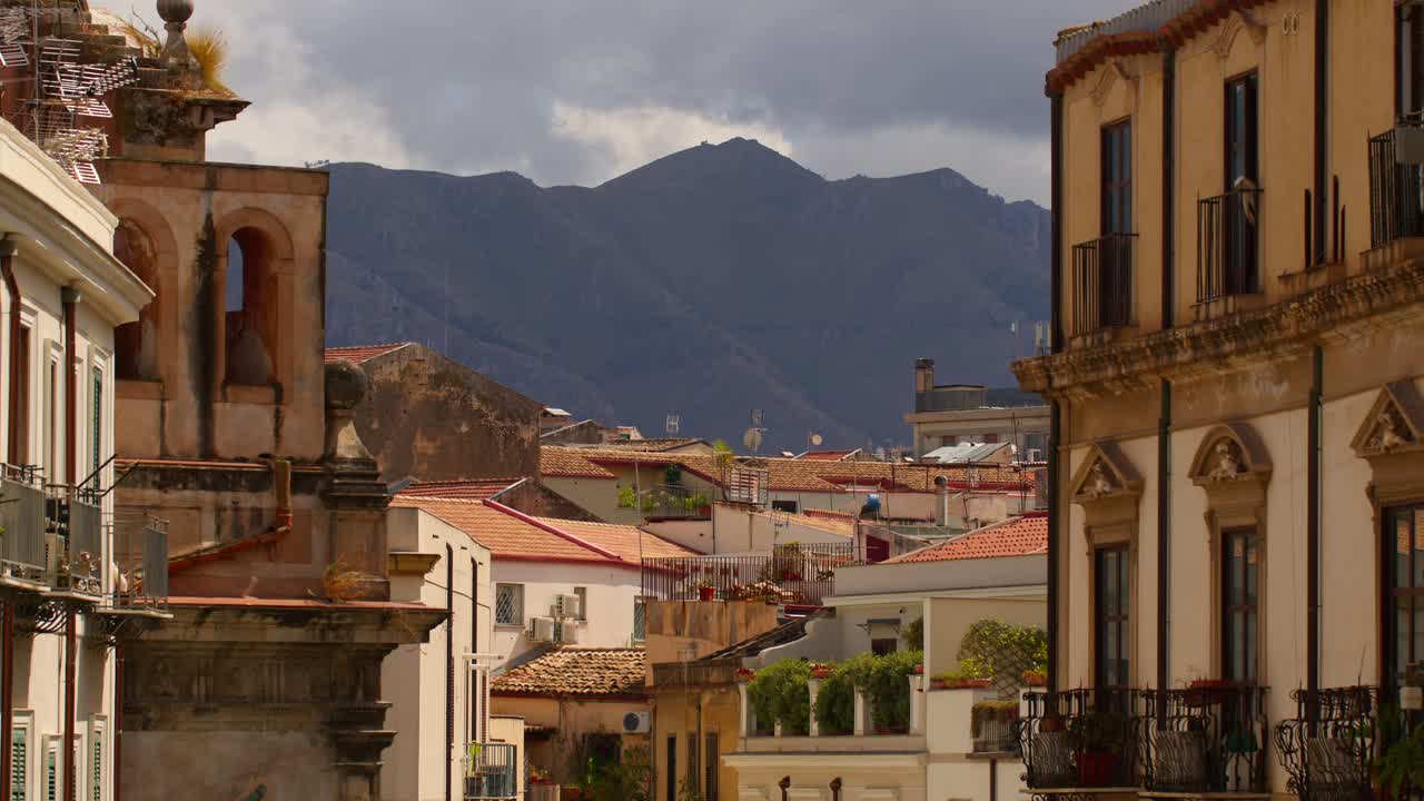Static shot showcasing beautiful rooftops in the centre of Palermo, Sicily, Italy (Palermo, Sicilia, Italia) with mountain backdrop during sunny day