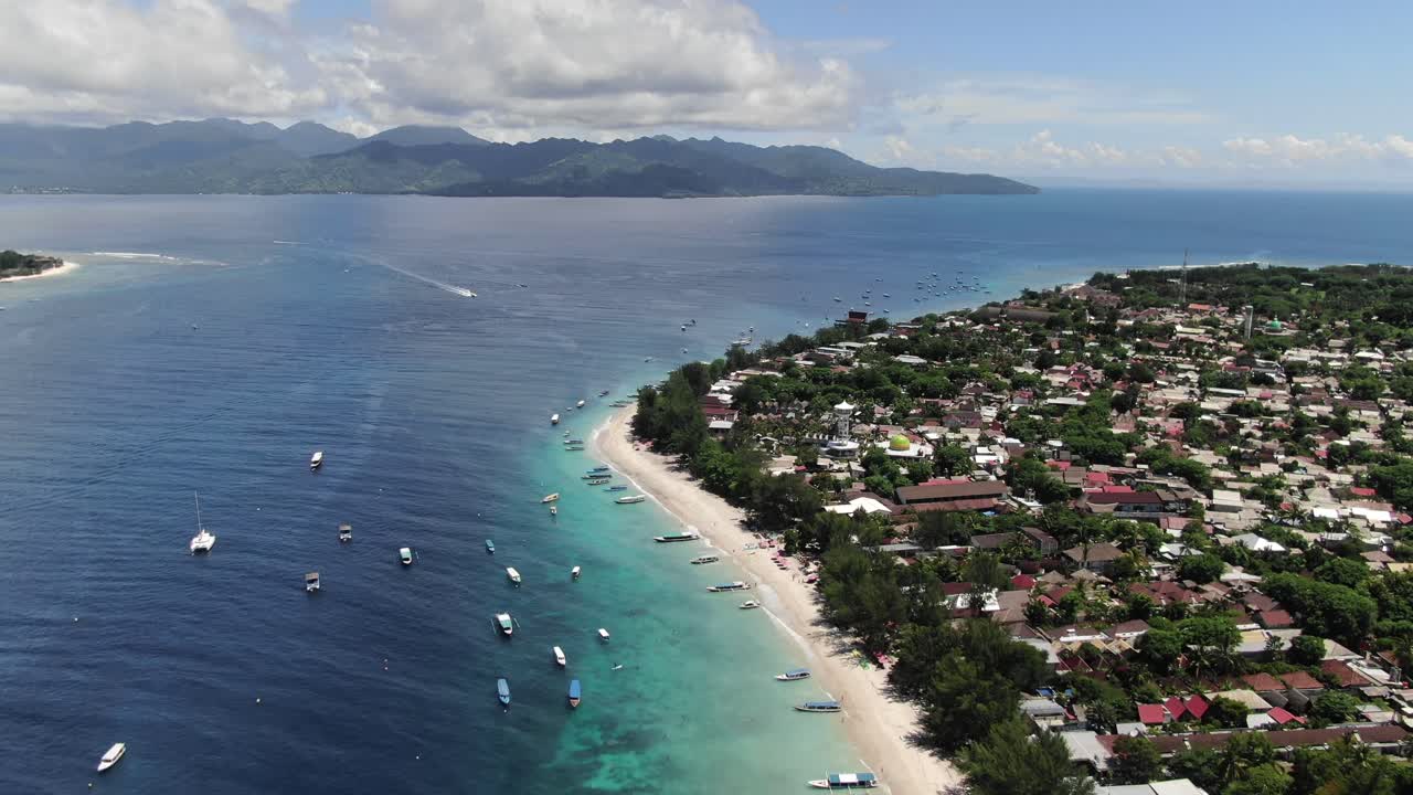 Flyover of Gili Trawangan beach with boats parked in the turquoise water