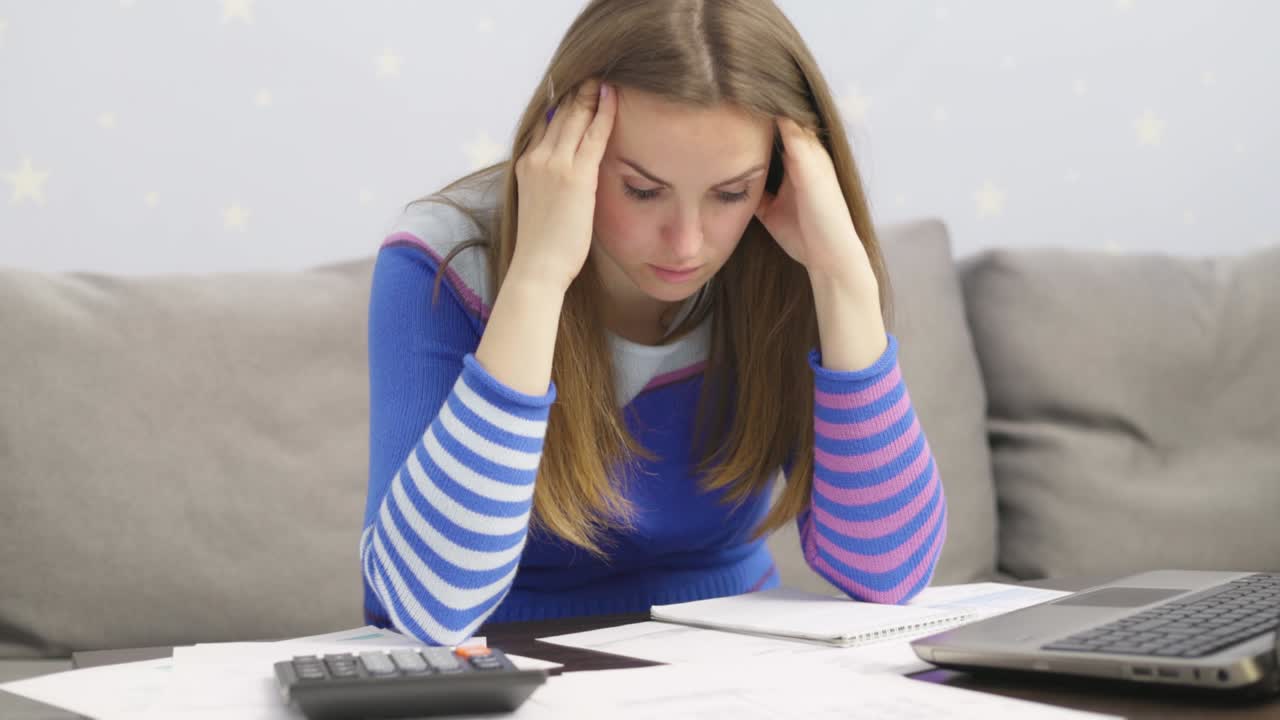 estresada joven morena se sienta en casa a administrar las finanzas del hogar frustrada con los problemas financieros de la familia. angustiada mujer molesta decepcionada con la deuda de dinero, paga facturas impuestos en línea en la computadora portátil