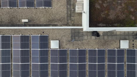Top-down-drone-lifting-shot-of-a-drone-flying-above-solar-panels-on-a-roof