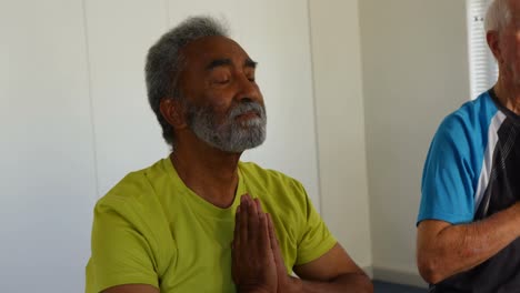 vista frontal de personas mayores activas de raza mixta realizando yoga en el estudio de fitness 4k