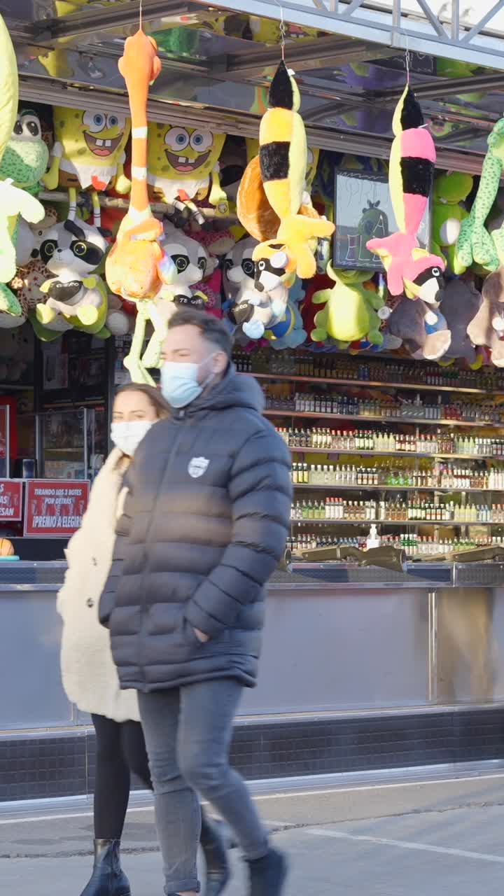 People enjoying a carnival game booth filled with prizes and stuffed animals