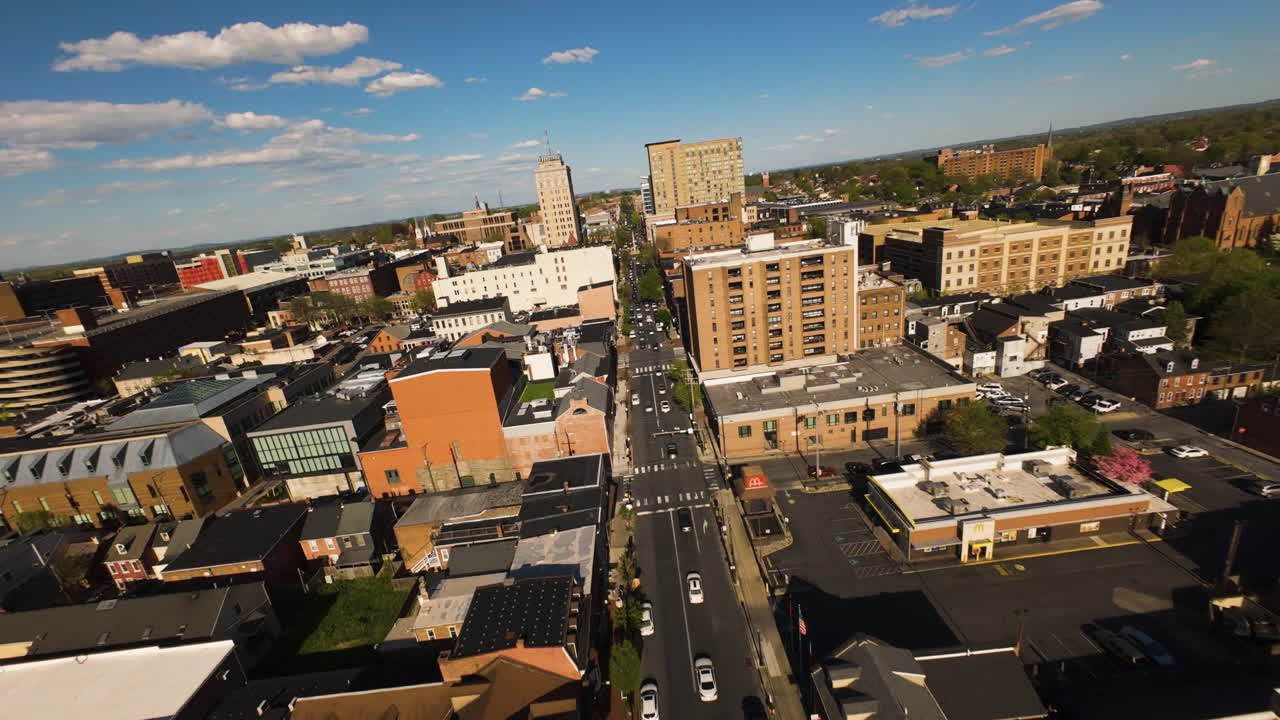FPV flight over main street of American town with traffic during golden sunset