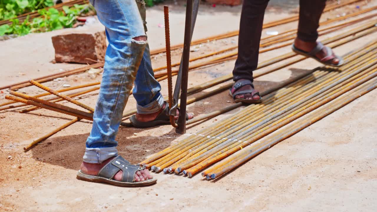Construction workers using steel bar bending lever to bend 16mm rod for column at construction site. day time, stable shot, 4k