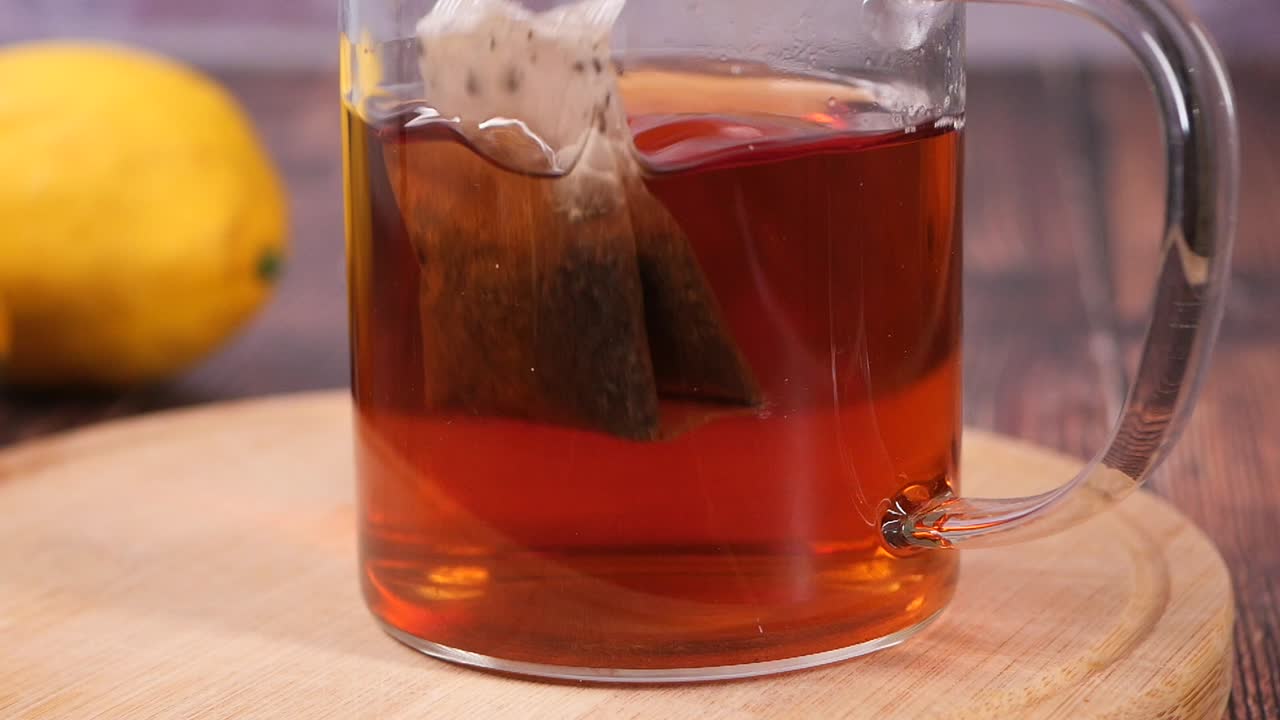 Bustina di tè in infusione in una tazza di vetro con acqua calda