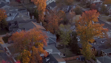 Aerial-over-suburban-neighborhood-in-Autumn-as-a-car-drives-down-the-street