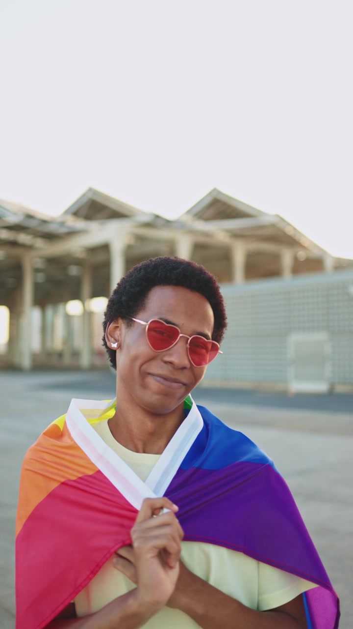 Happy Young Person Wrapped in Rainbow Pride Flag and Heart Sunglasses