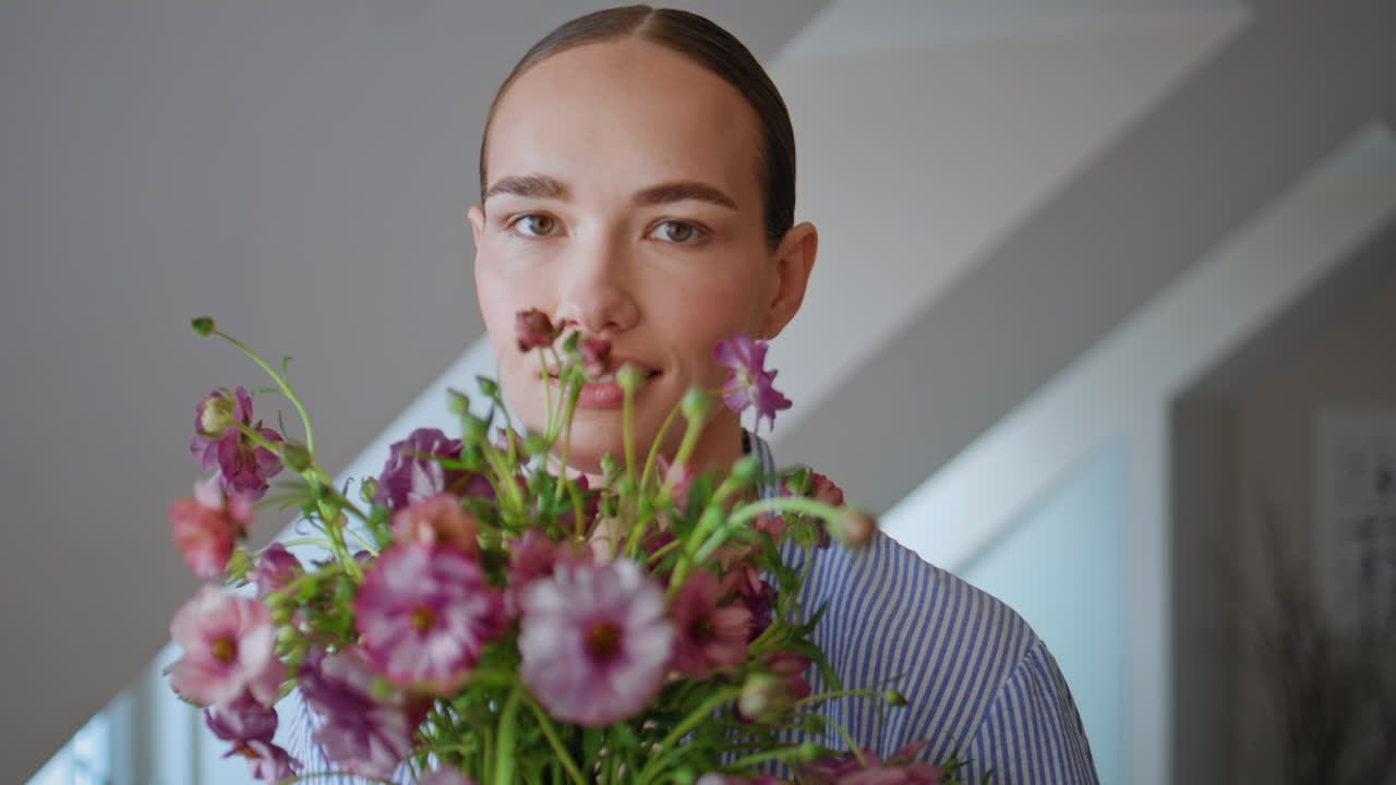 Romantic woman sniffing wildflowers looking camera at flat closeup. Girl posing