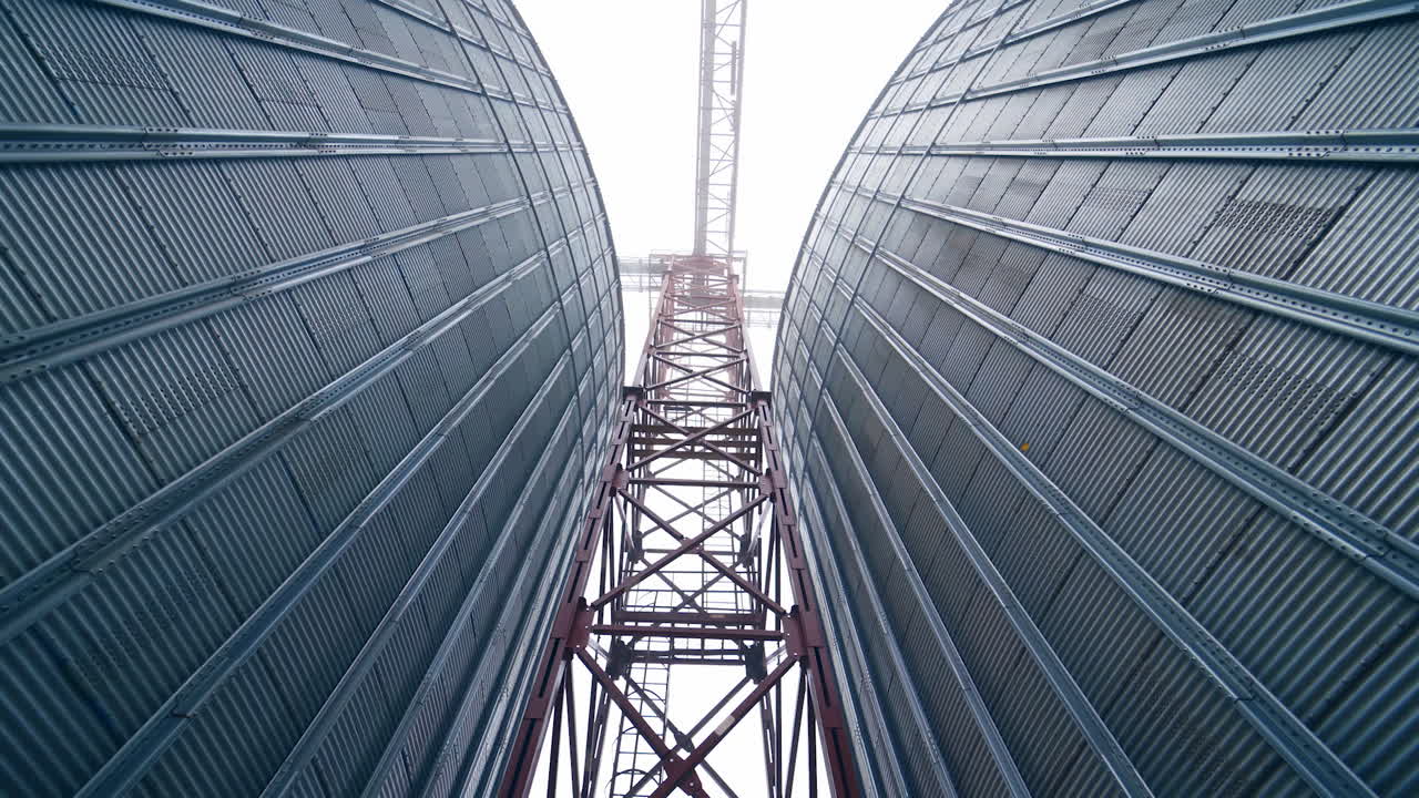 High metal support between two tanks of grain dryer. A walk between the huge tanks right under the metal support. View from below.
