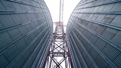 high metal support between two tanks of grain dryer. a walk between the huge tanks right under the metal support. view from below.