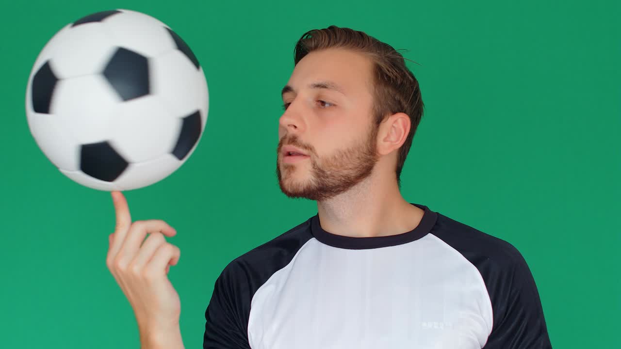 jugador de fútbol girando una pelota en un dedo, fondo de pantalla verde, 4k cámara lenta
