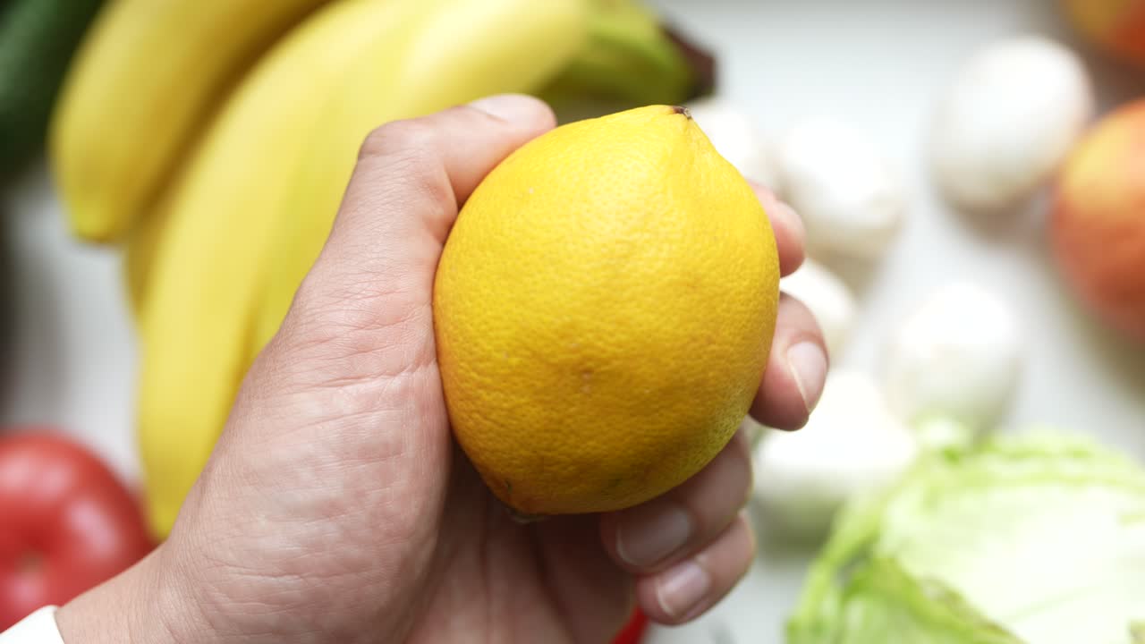 mano sosteniendo un limón con frutas y verduras