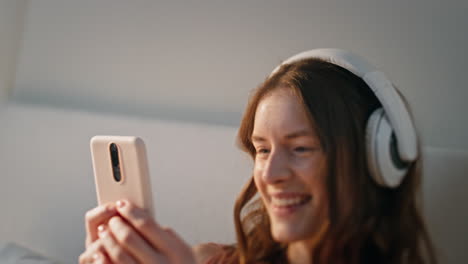 joyful teenager typing mobile phone in headphones closeup. carefree girl listen