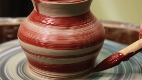 hands on pottery wheel. craftsman artist painting pot with brush