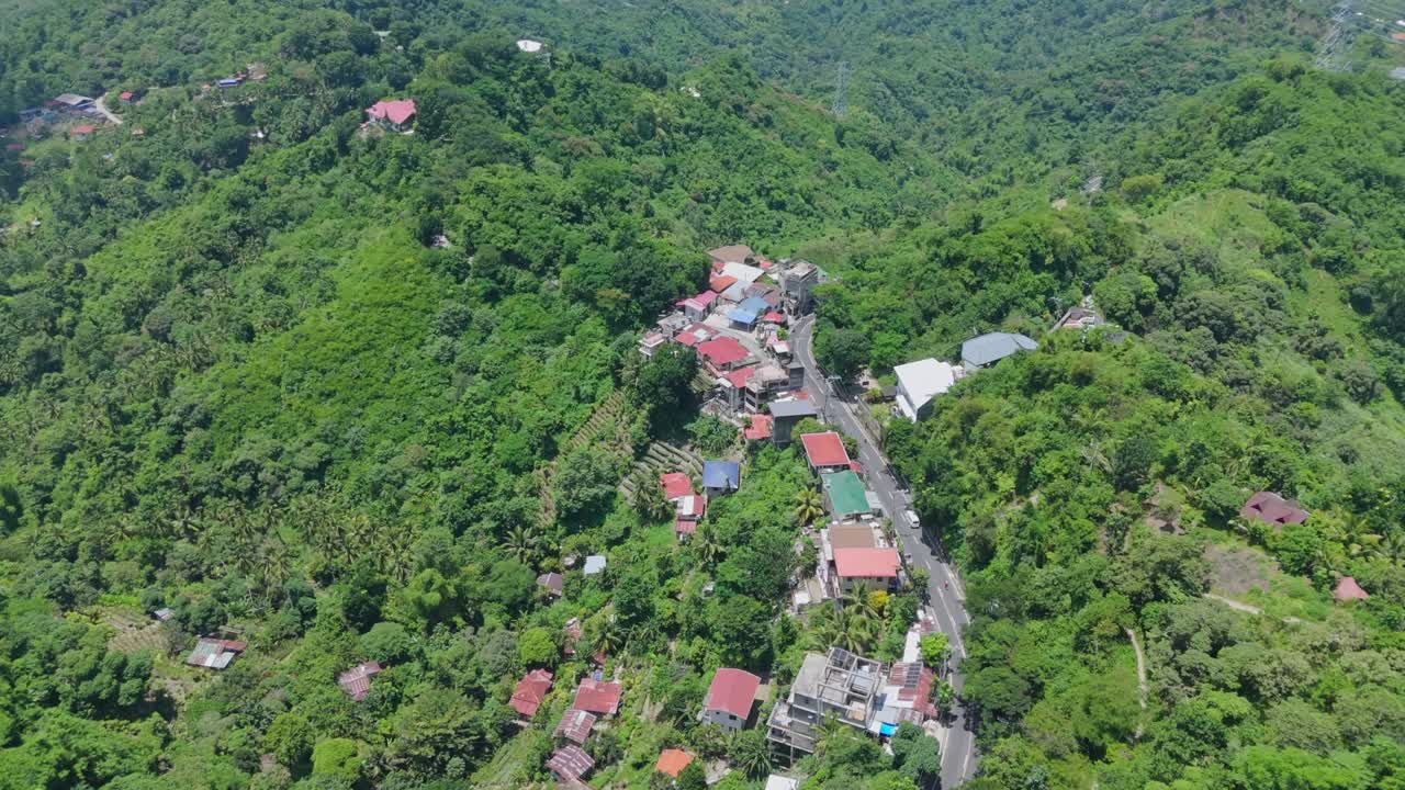 Drone view of a secluded mountain village surrounded by dense tropical forest. Perfect for themes of nature, isolation, travel, or sustainability