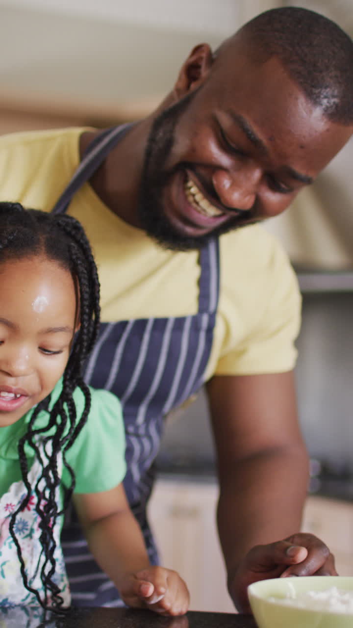 Video verticale di un padre e una figlia afroamericani felici che preparano la pizza insieme in cucina